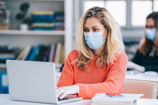 Woman with face mask sitting at a computer