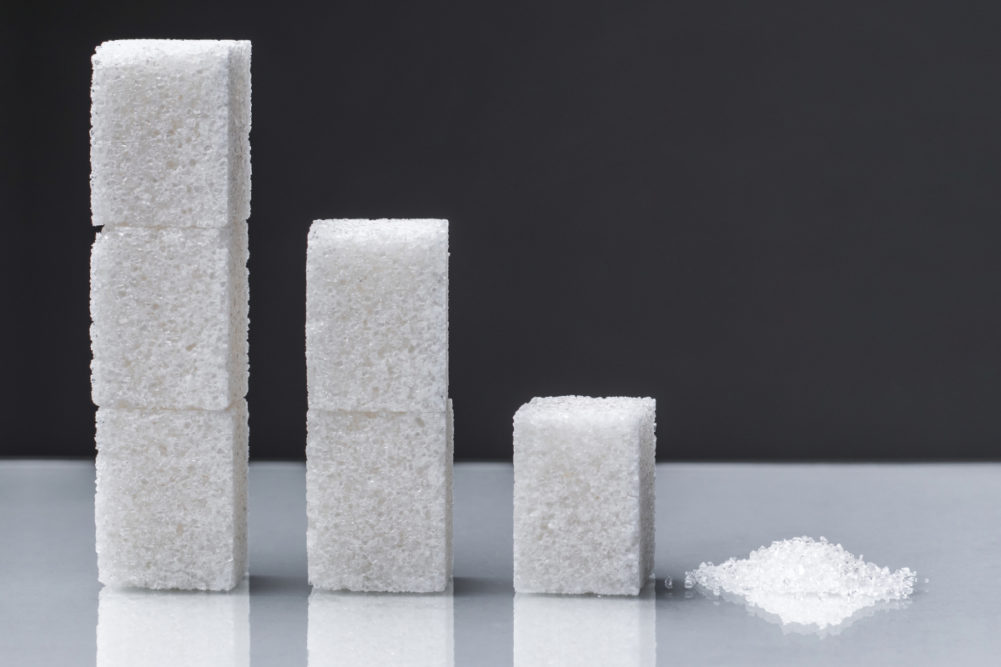 Stacks of sugar cubes descending into a small pile of sugar.