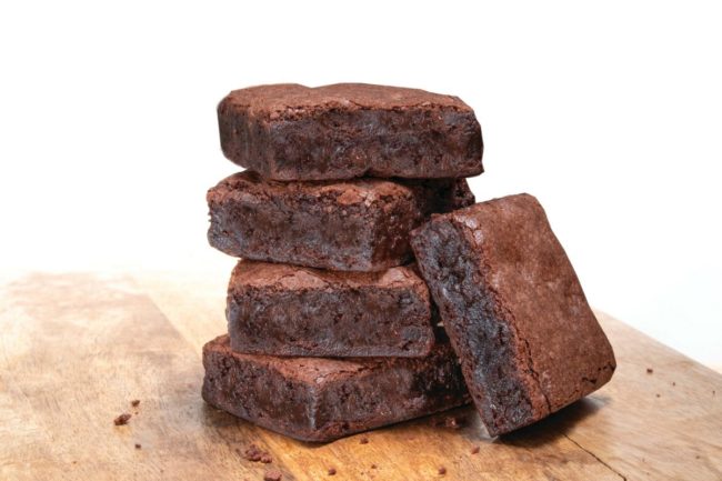 Five brownies on a wooden table. 