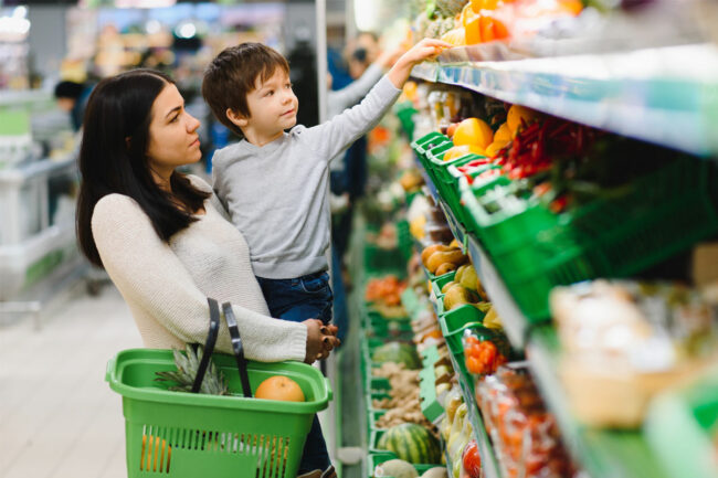 Woman and her child in grocery store produce section. 