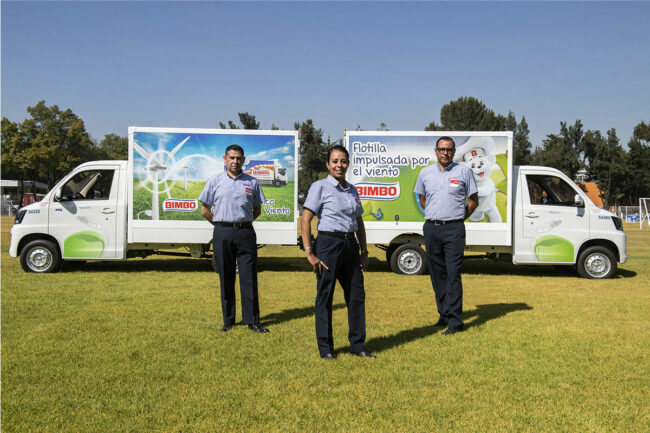 Grupo Bimbo employees stand outside near a bread truck. 