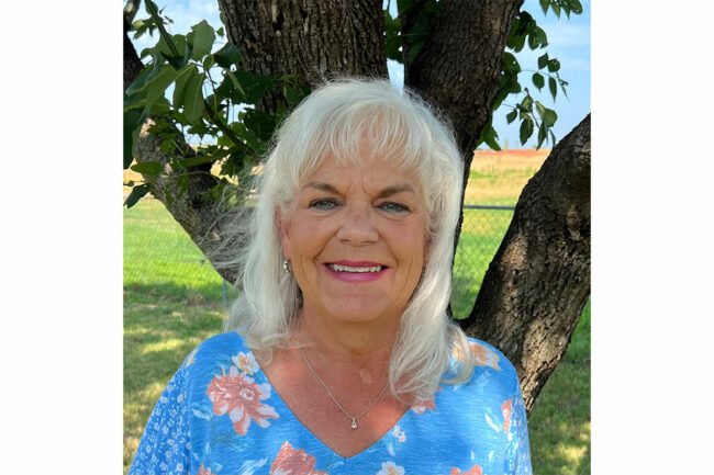 Christine Kirby wears blue dress on sunny day.