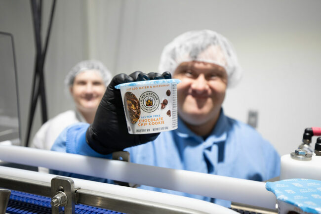 Employee shows camera the new King Arthur Baking Co. mixture. 