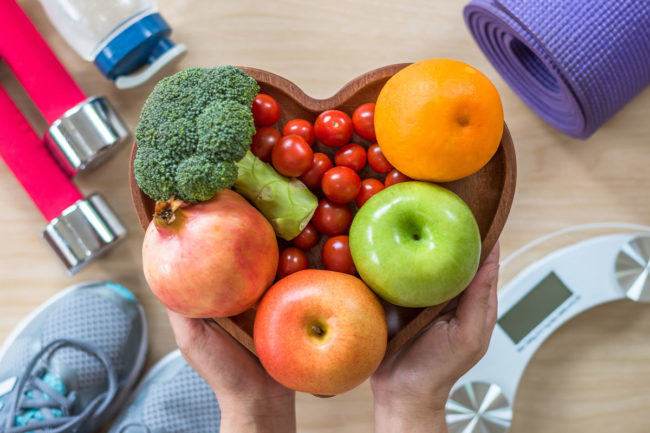 An assortment of healthy fruits and vegetables including broccoli and apples.