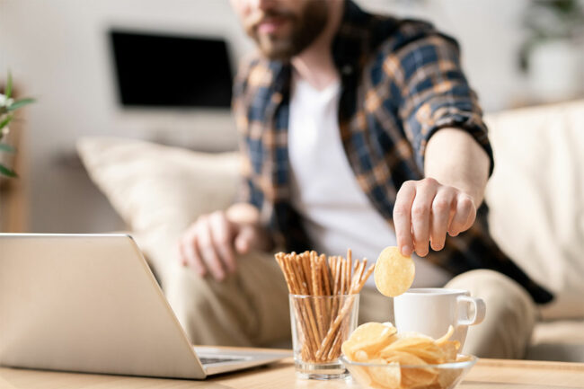 A man snacks while working from home. 