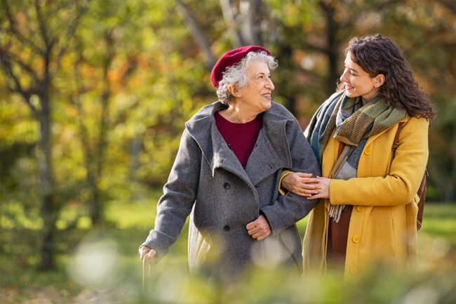 A grandmother and granddaughter walking in the park.