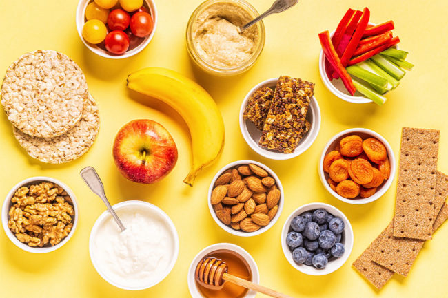 Assortment of healthy snacks, including nuts, fruit and whole grain crackers.