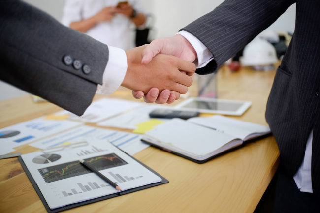 Two businessmen shaking hands in boardroom. 