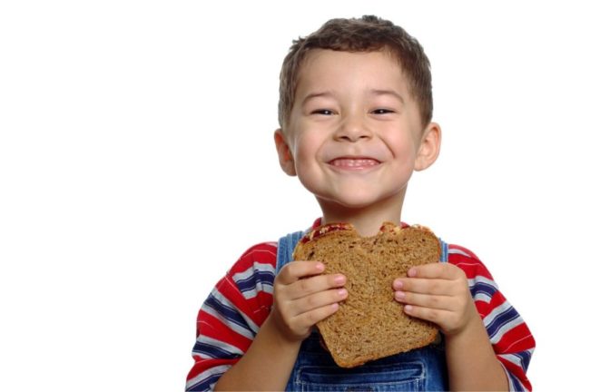 Child eating a slice of whole grain bread. 