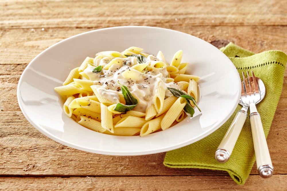 Bowl of penne pasta with white sauce. 