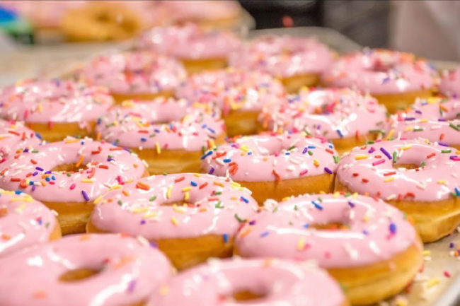 Donuts with pink icing on the line at Glenn Wayne Bakery. 