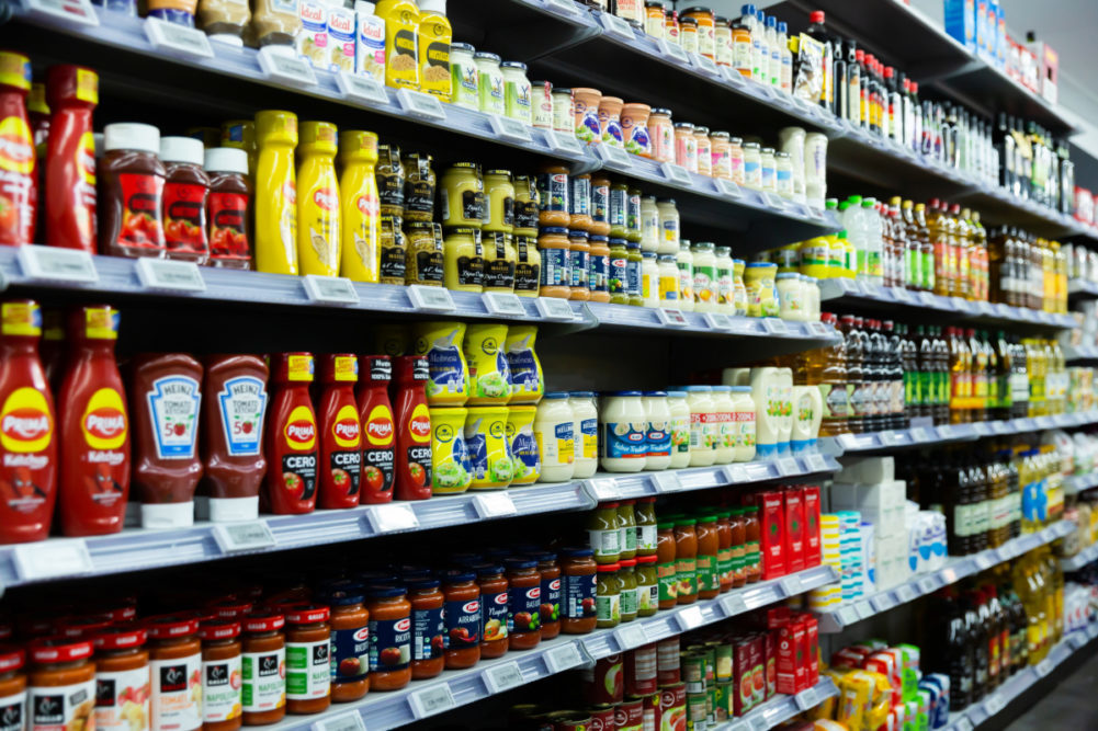 Assortment of condiments on grocery store shelf. 