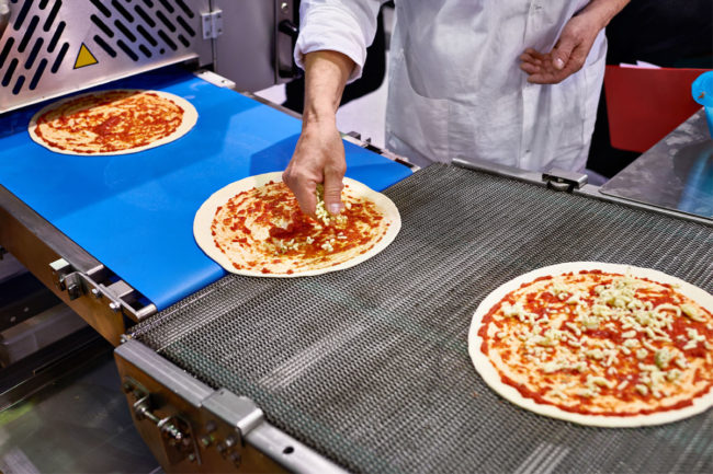 Pizzas on conveyor belt. 