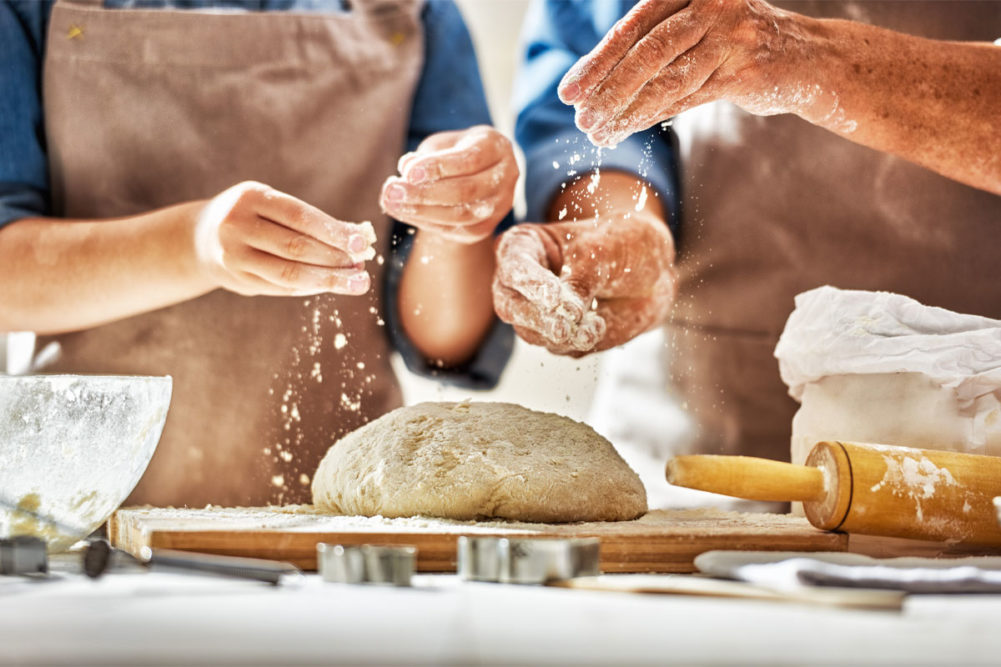 Hands of two bakers kneading dough. 