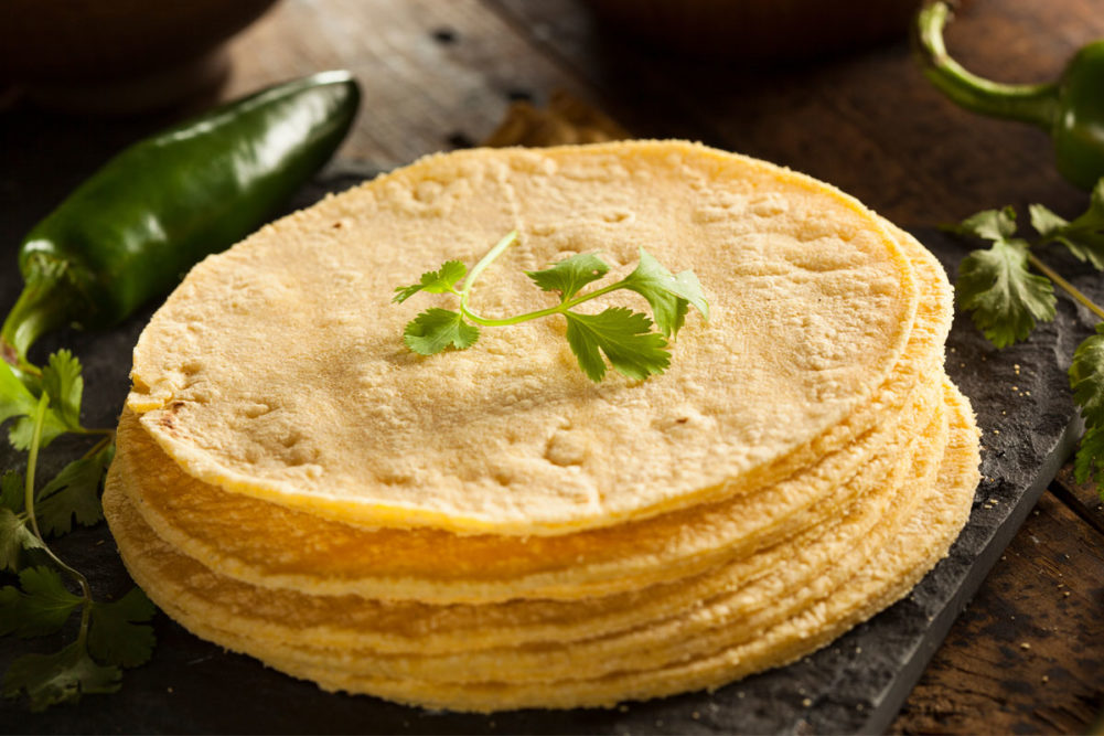 Stack of corn tortillas with cilantro on top.