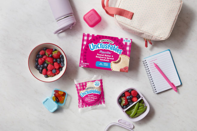 New Uncrustable in lunchbox with bowl of berries. 