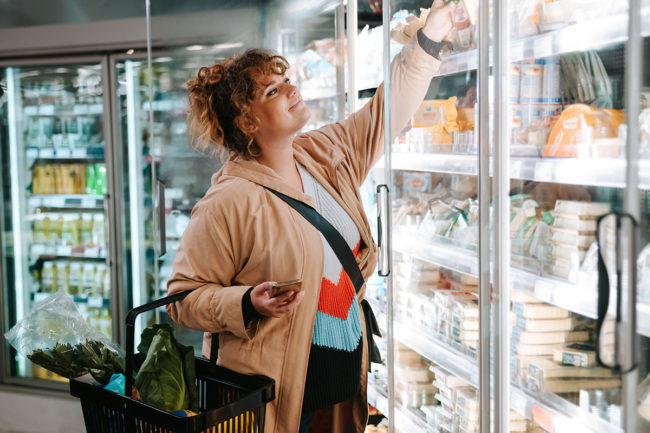 Woman grocery shopping in dairy aisle.