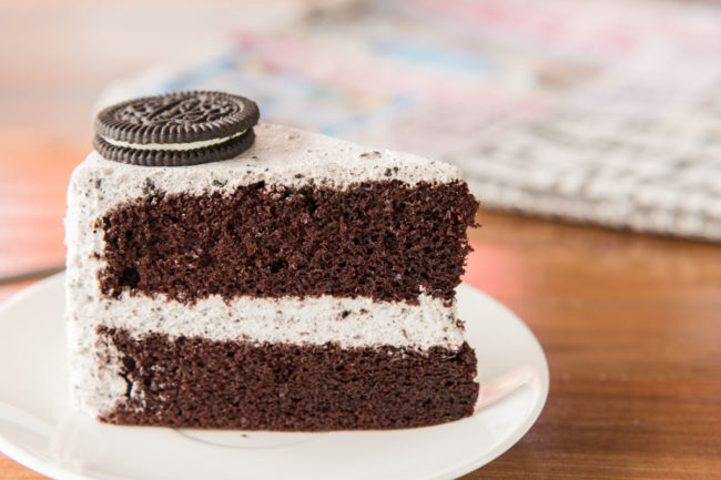 A slice of Oreo cheesecake on white plate. 