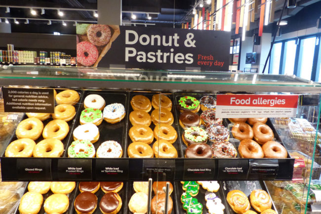 Donut case at grocery store full of fresh donuts. 