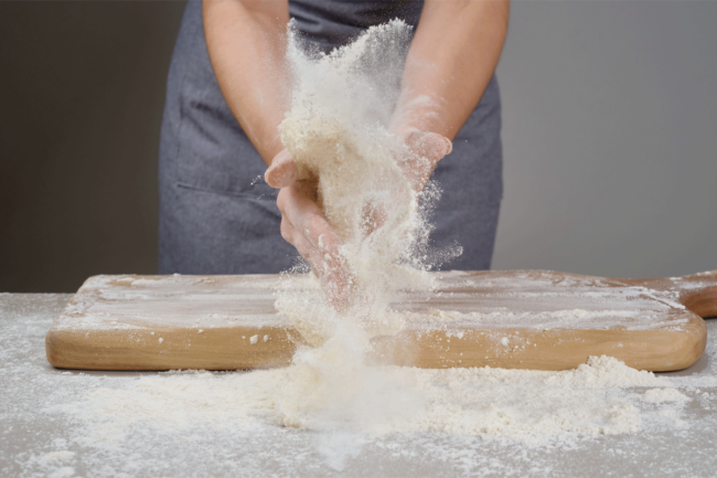 Woman baker rolls dough. 