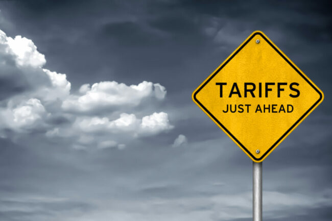 Road sign on cloudy day reading "Tariffs Just Ahead." 