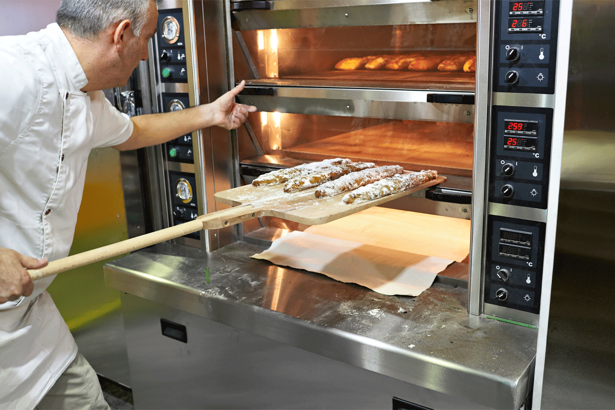 Baker placing bread in oven.