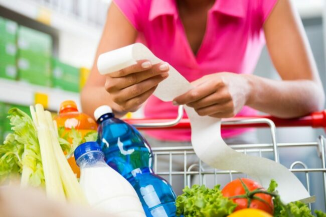 Woman checking receipt in grocery cart. 